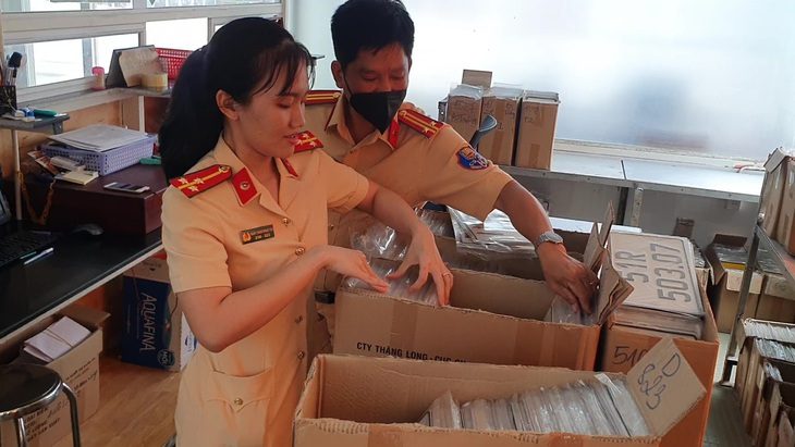 Cục bất ngờ đổi quy định, dân chơi biển số đẹp nói bị ‘sụp hầm’ - Ảnh 1. Cán bộ cảnh sát giao thông ở TP.HCM cấp biển số cho người dân - Ảnh: MINH HÒA